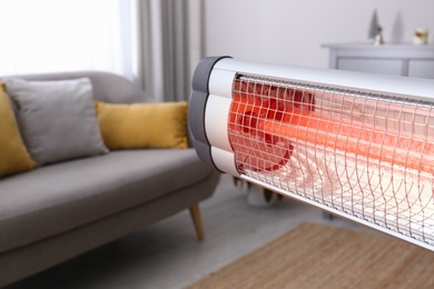 Photo of Modern electric infrared heater in room, closeup. Space for text