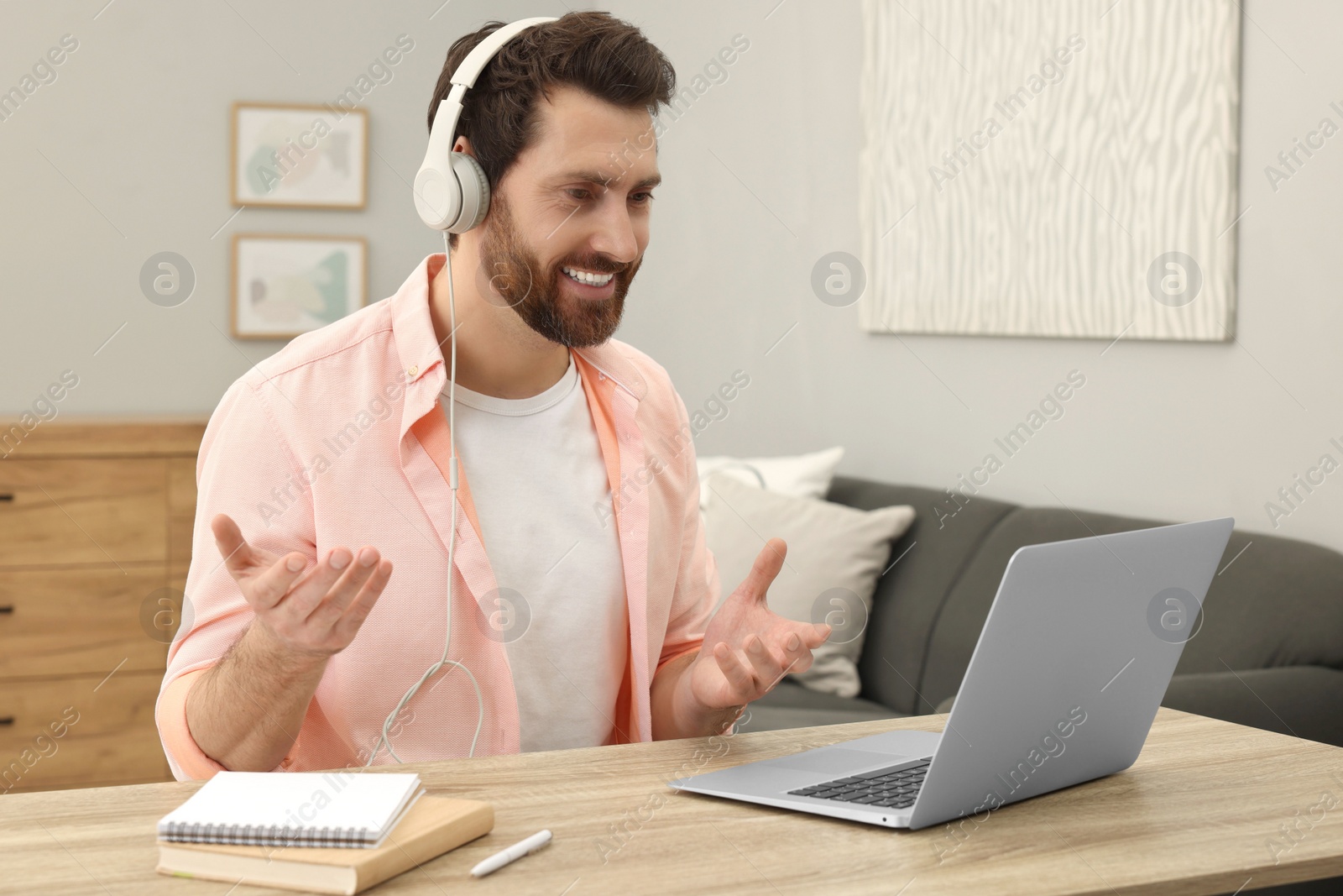 Photo of Man in headphones having video chat via laptop at home