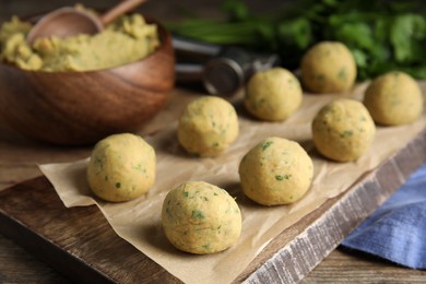 Wooden board with raw falafel balls on table, closeup