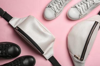 Photo of Flat lay composition of stylish shoes and bum bags on color background