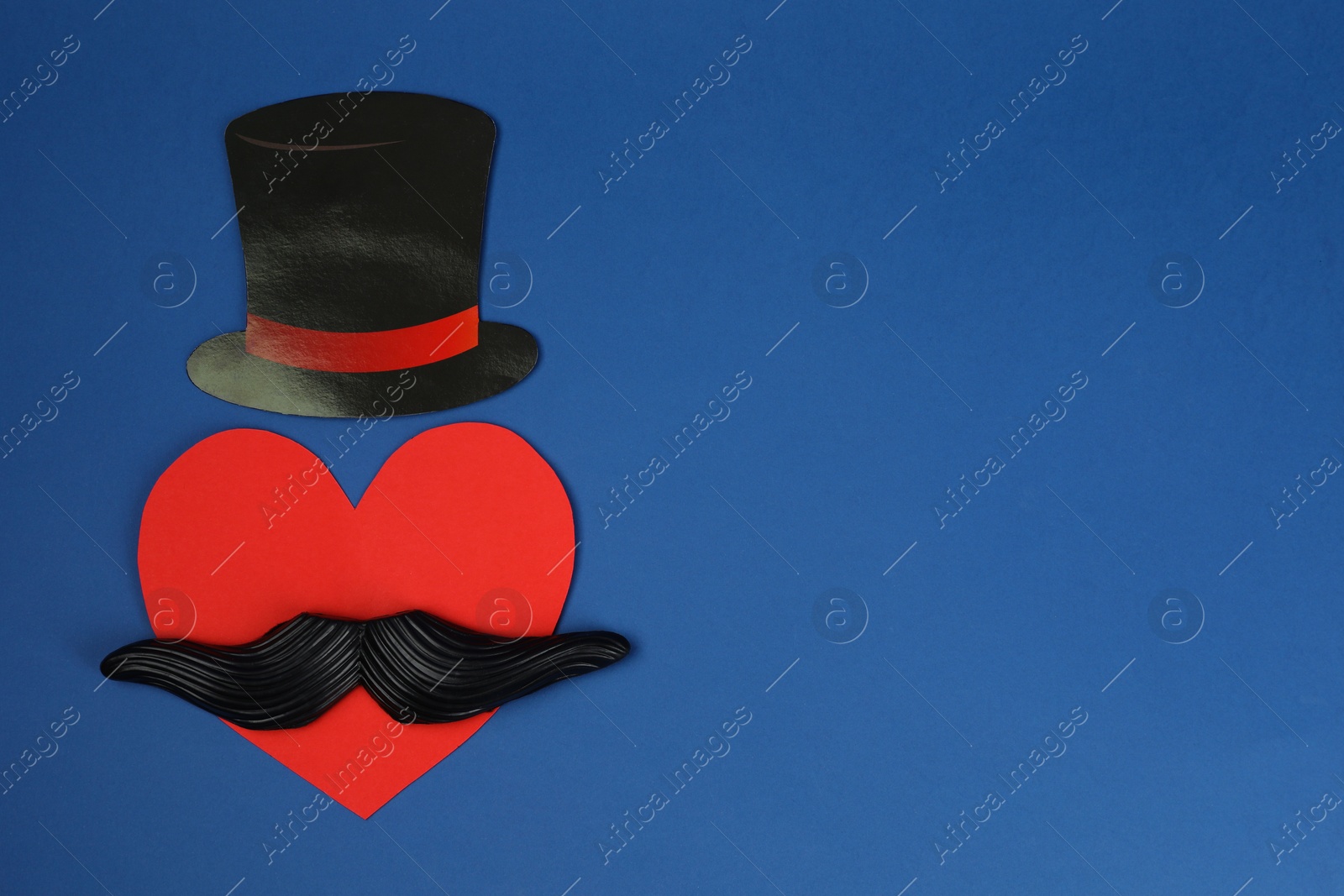 Photo of Fake mustache, paper hat and heart on blue background, top view. Space for text