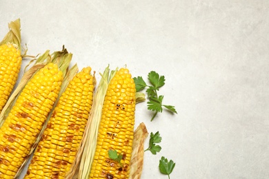 Photo of Delicious grilled corn cobs on light table, flat lay. Space for text