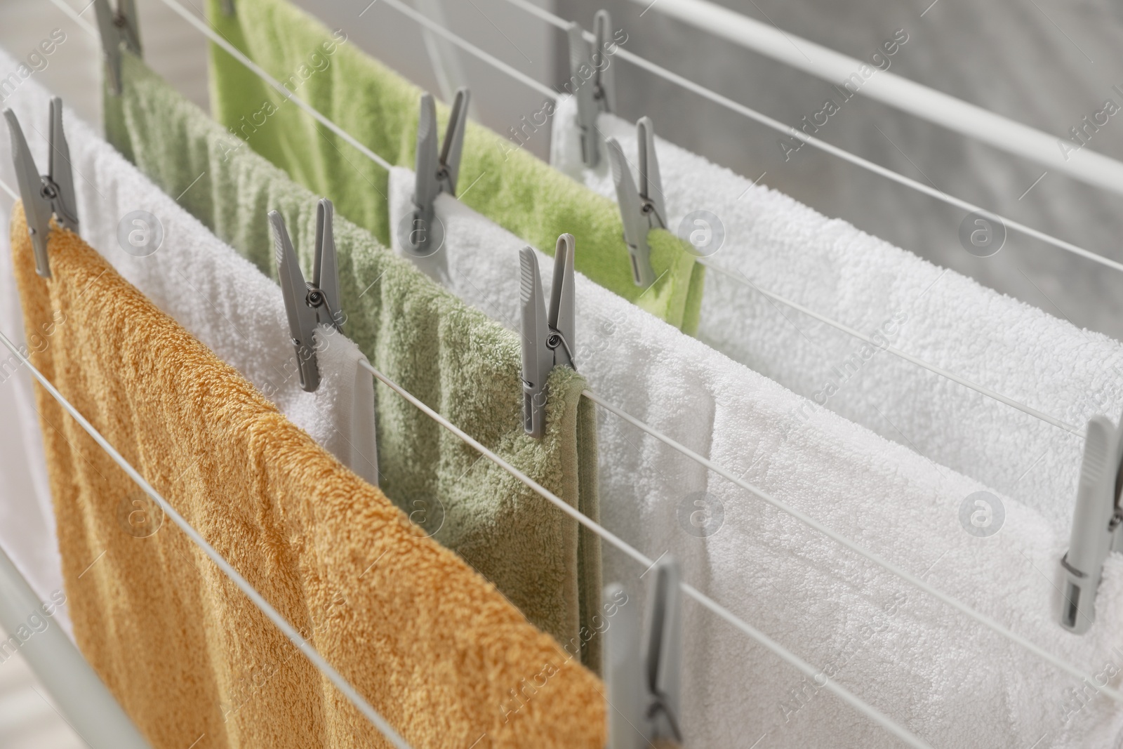 Photo of Clean terry towels hanging on drying rack, closeup