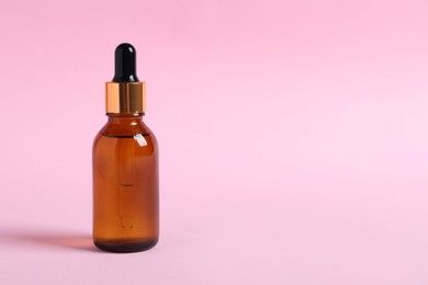 Photo of Bottle with cosmetic oil on pink background. Space for text