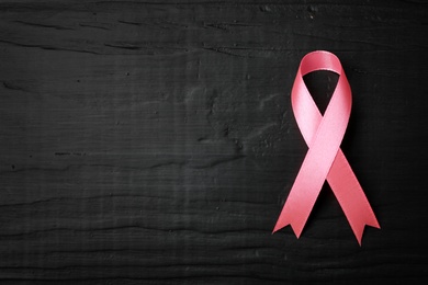 Photo of Pink ribbon on wooden background, top view with space for text. Breast cancer concept