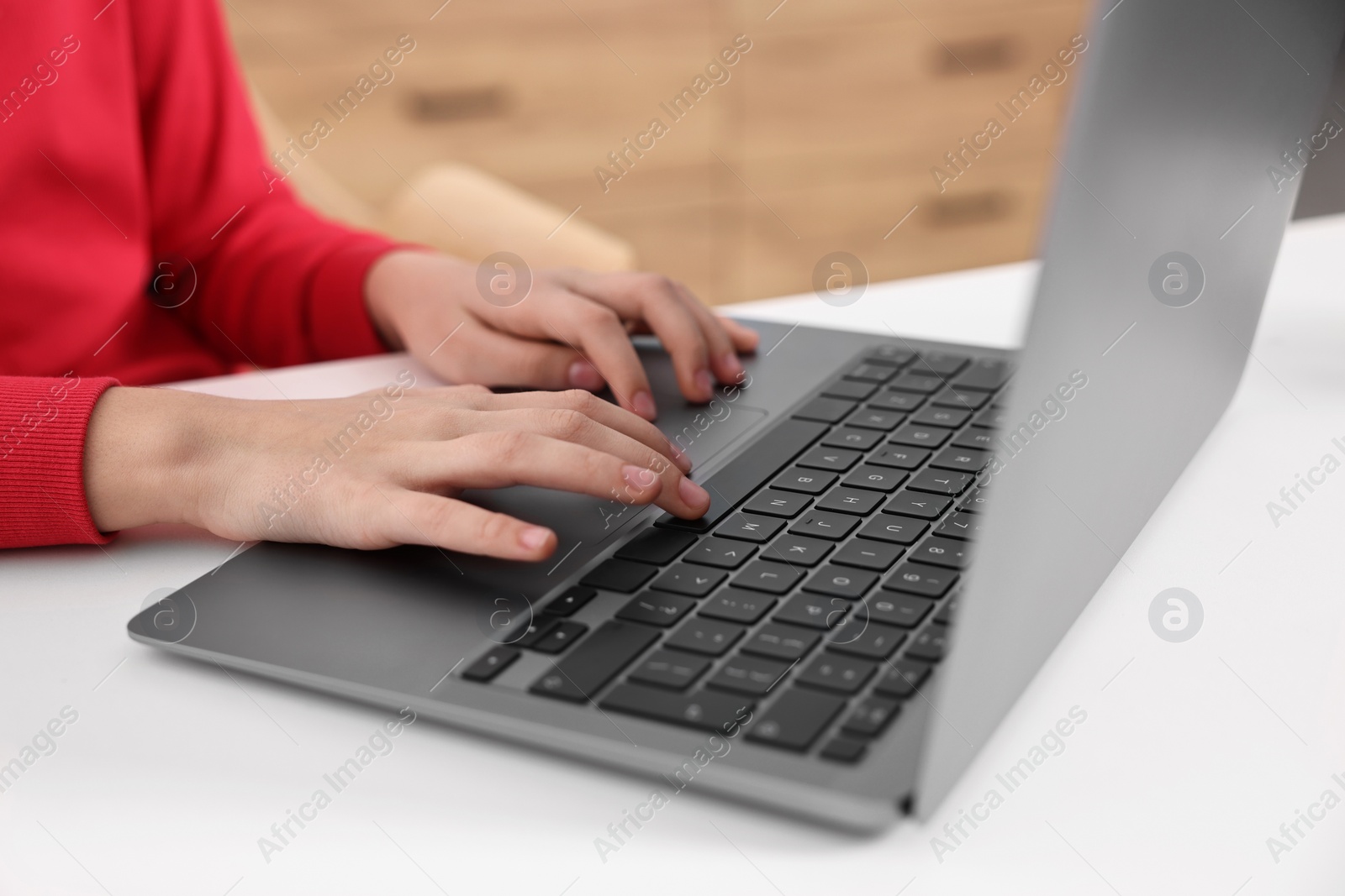 Photo of E-learning. Girl using laptop during online lesson at table indoors, closeup