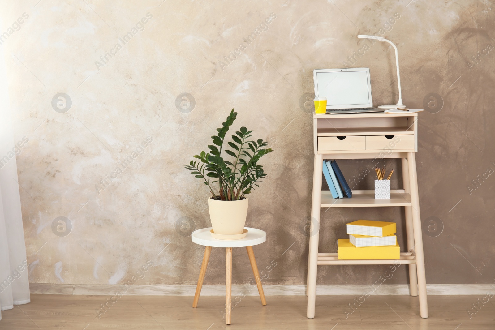 Photo of High wooden table with laptop as stand up workplace in modern interior