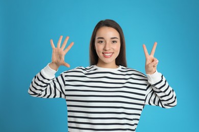 Photo of Woman showing number seven with her hands on light blue background