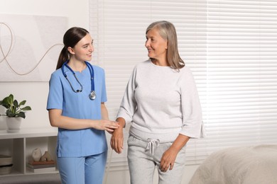 Young healthcare worker assisting senior woman indoors