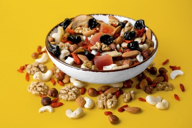 Photo of Bowl with mixed dried fruits and nuts on yellow background