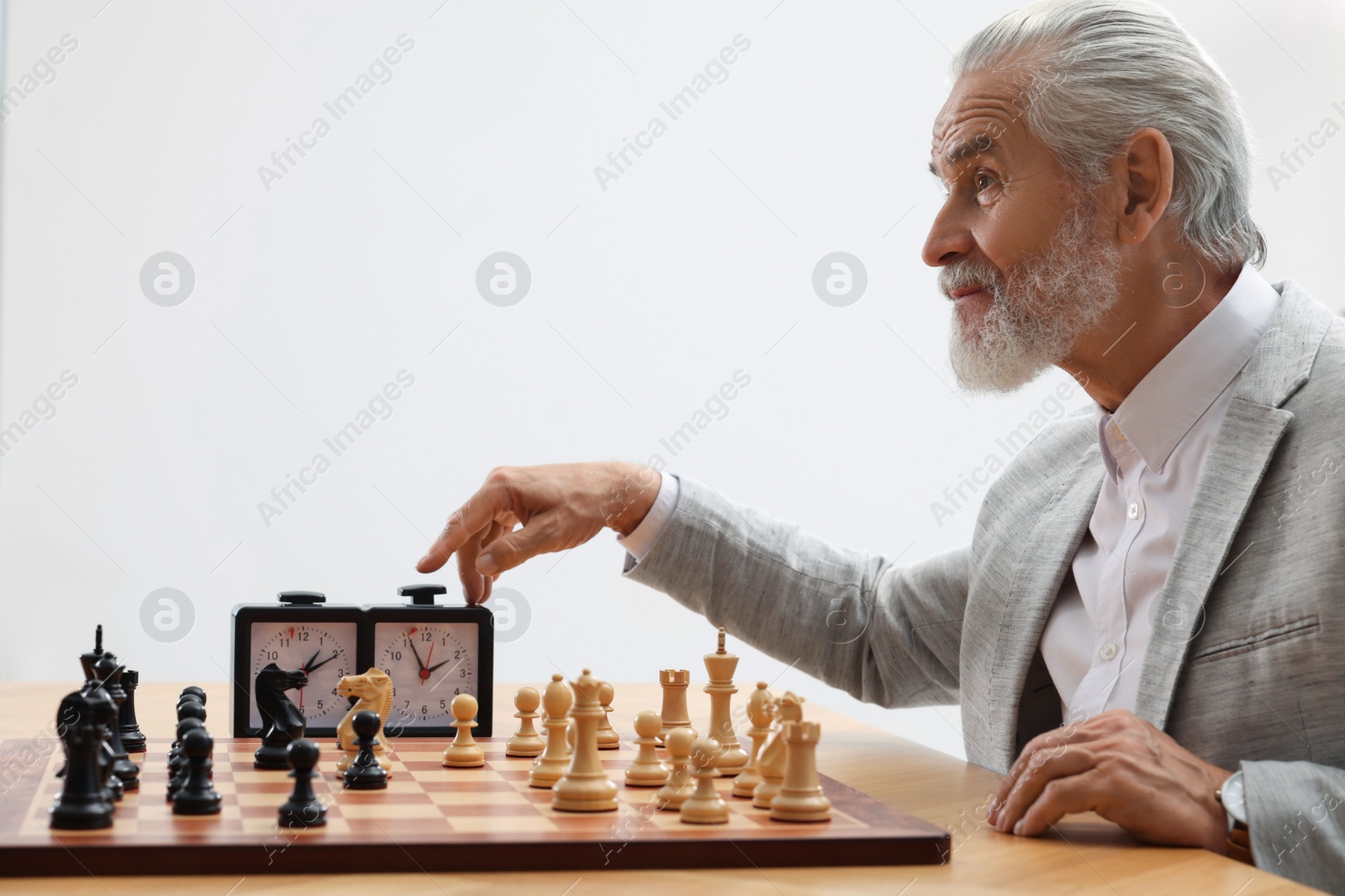 Photo of Man turning on chess clock during tournament at table against white background