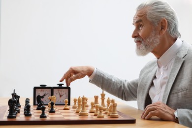 Photo of Man turning on chess clock during tournament at table against white background
