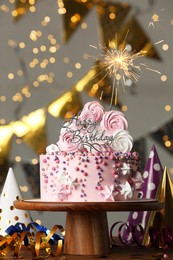 Photo of Beautiful birthday cake with burning sparkle and decor on wooden table