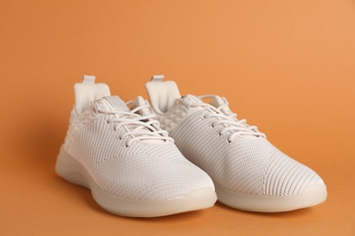 Photo of Pair of stylish sport shoes on orange background, closeup