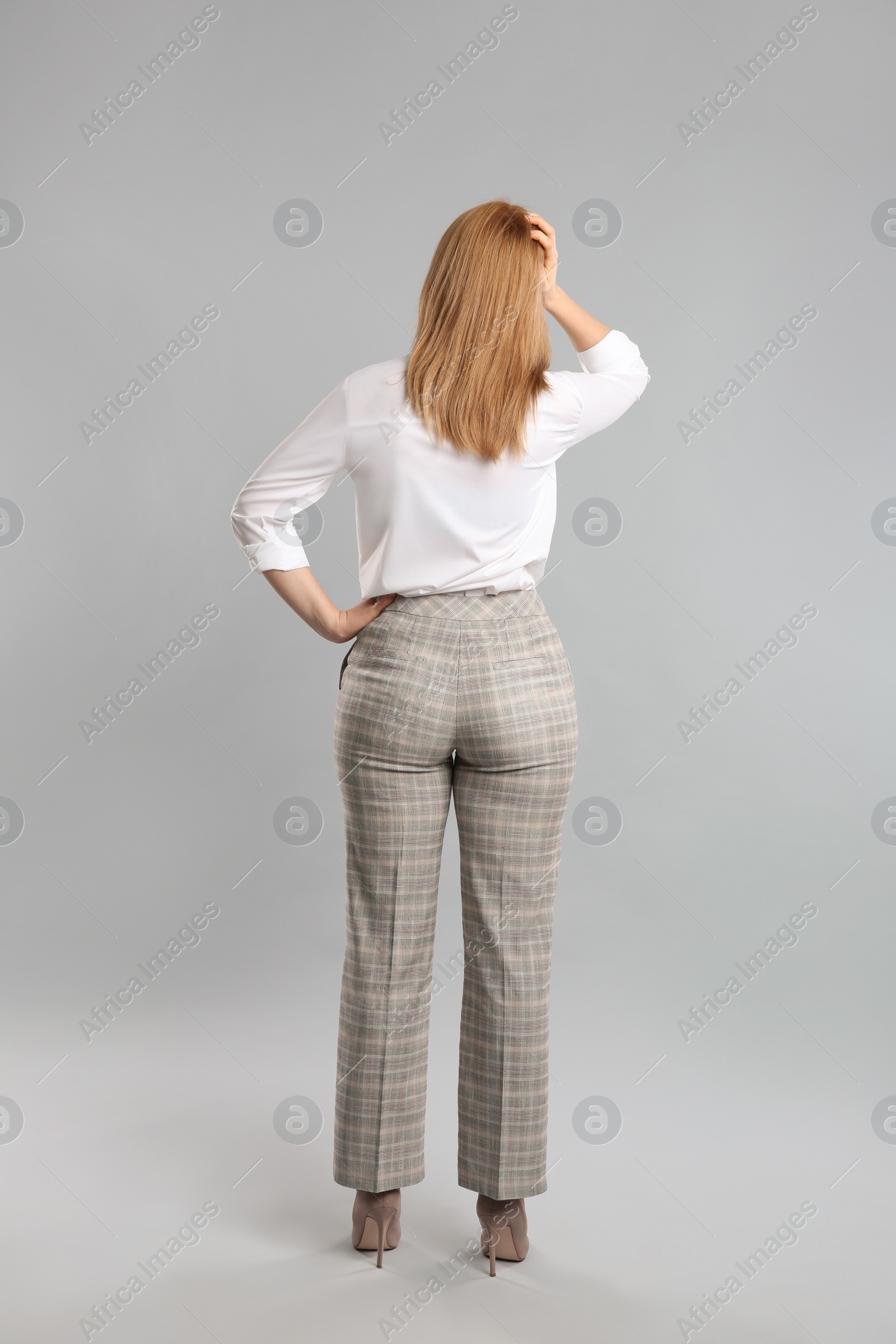 Photo of Young woman on grey background, back view