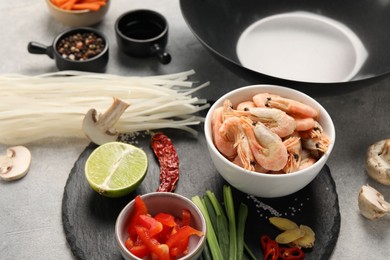 Different products and black wok on grey table, closeup