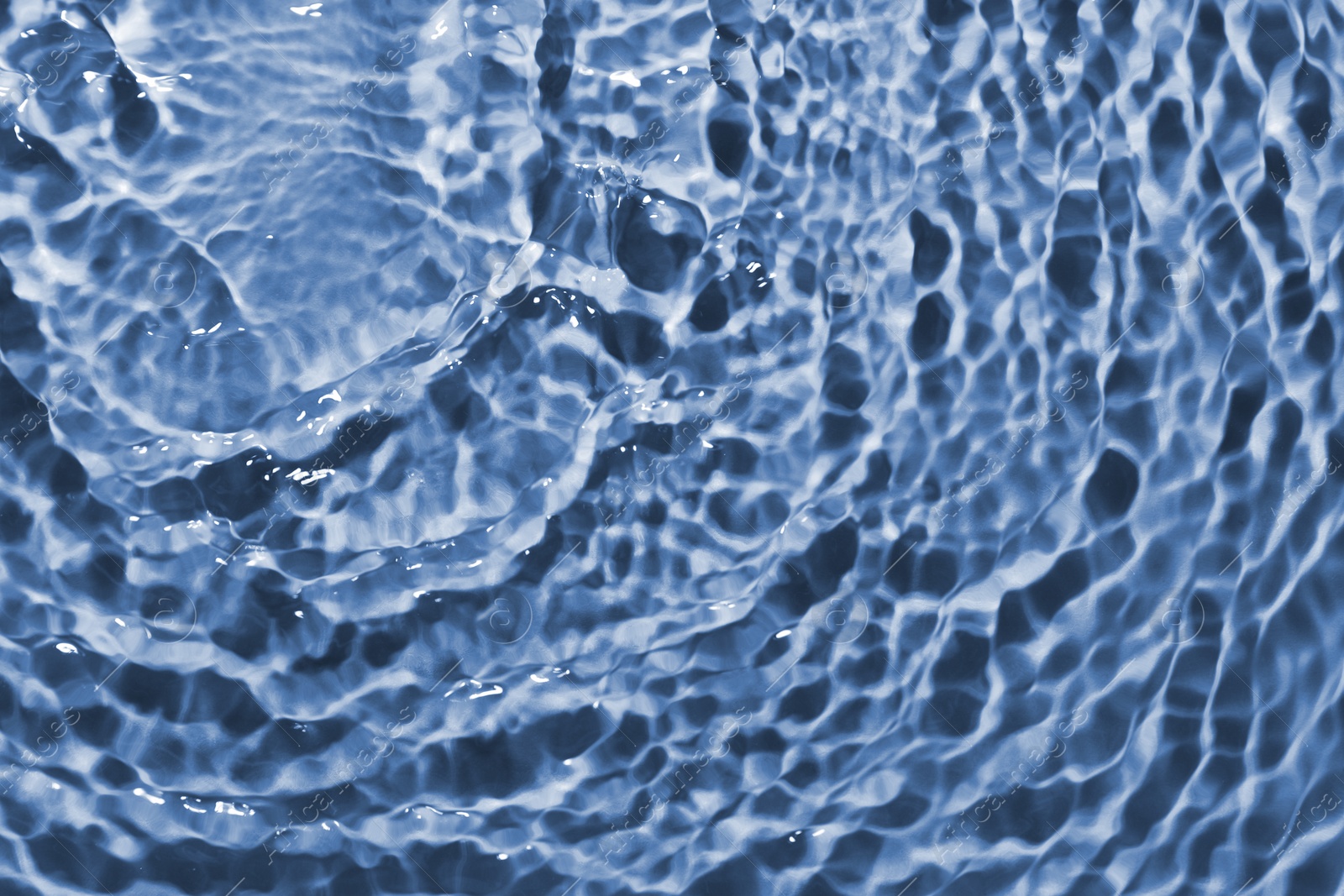 Image of Rippled surface of clear water on light blue background, closeup