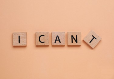 Photo of Motivation concept. Changing phrase from I Can't into I Can by removing square with letter T on pale coral background, top view