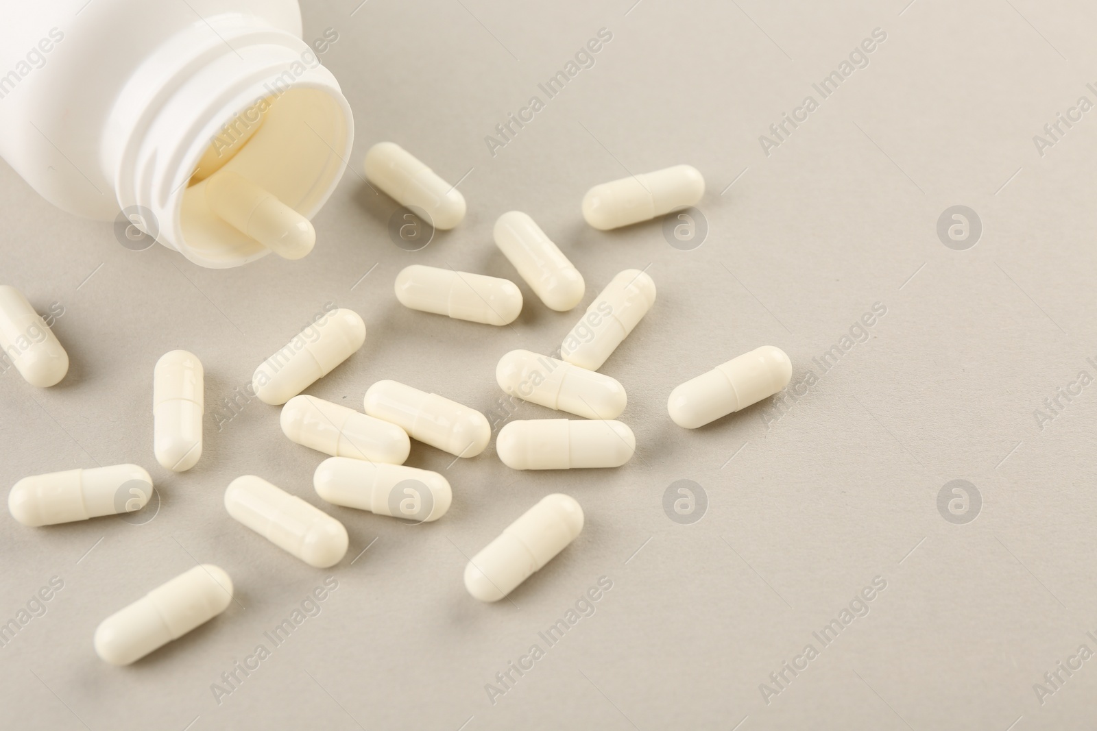 Photo of Bottle and vitamin capsules on light background, closeup. Space for text