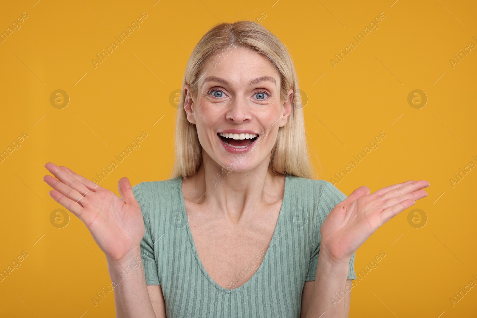 Photo of Portrait of happy surprised woman on yellow background