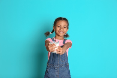 Photo of Adorable African-American girl with glass of milk on color background