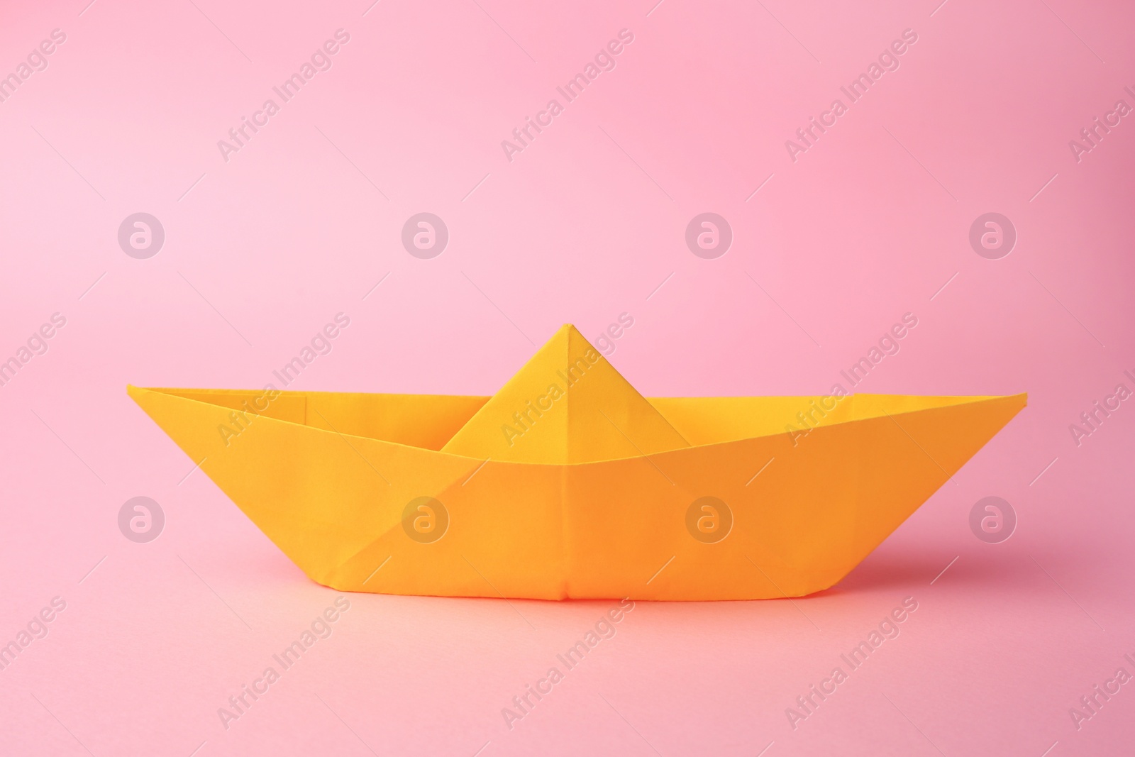 Photo of Origami art. Paper boat on pink background