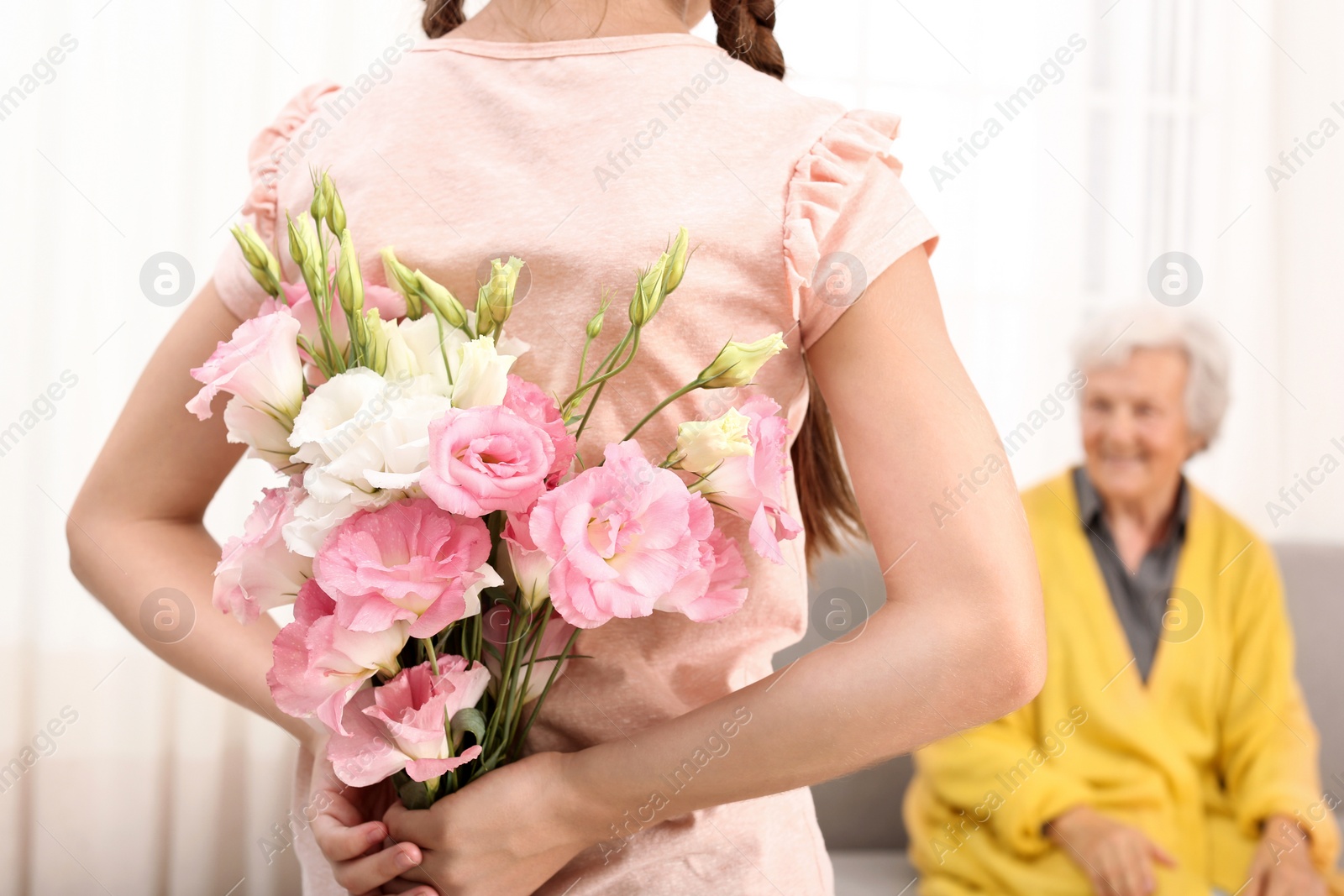 Photo of Girl congratulating her grandmother at home, closeup