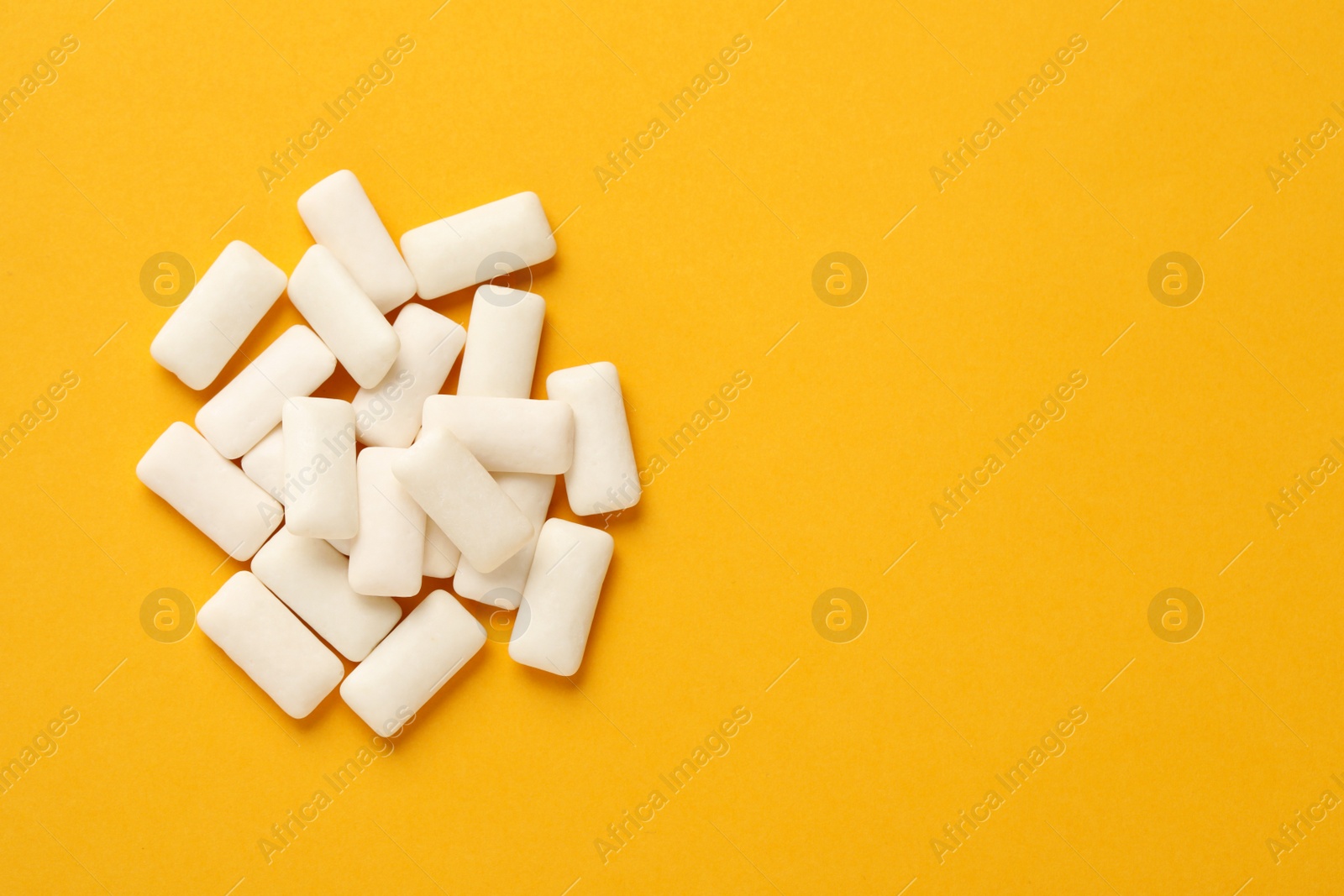 Photo of Many chewing gum pieces on orange background, flat lay. Space for text