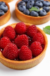 Photo of Tartlet with fresh raspberries on white table, closeup. Delicious dessert