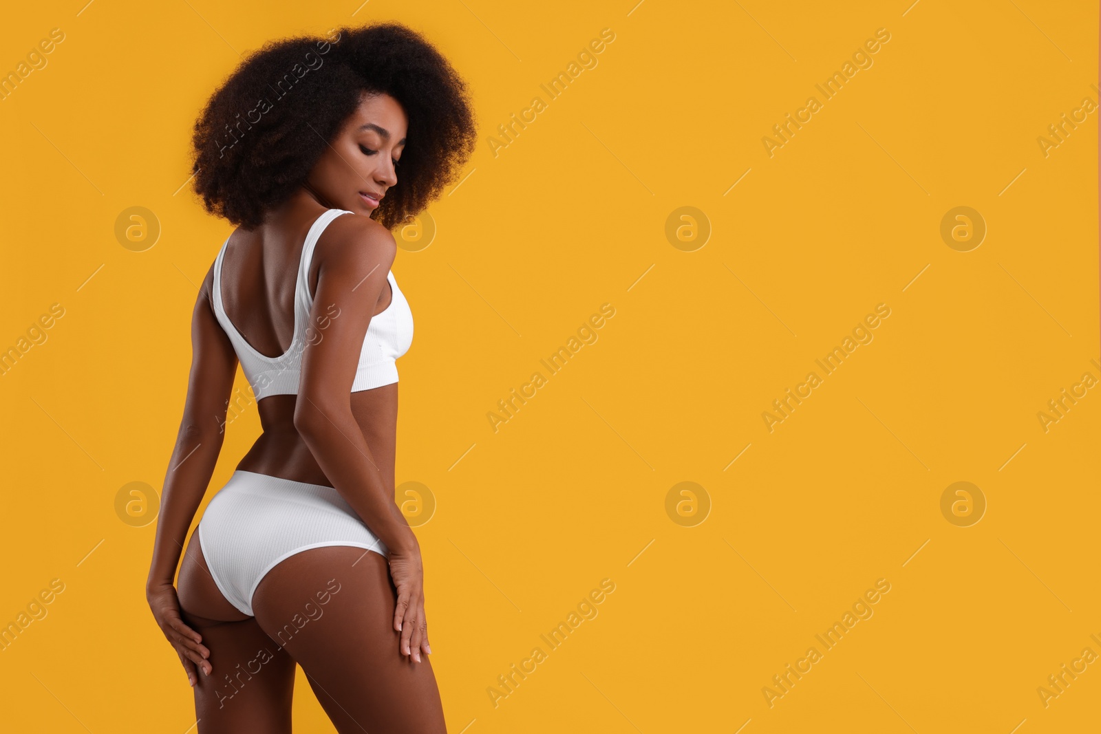 Photo of Beautiful woman in stylish bikini on yellow background, space for text