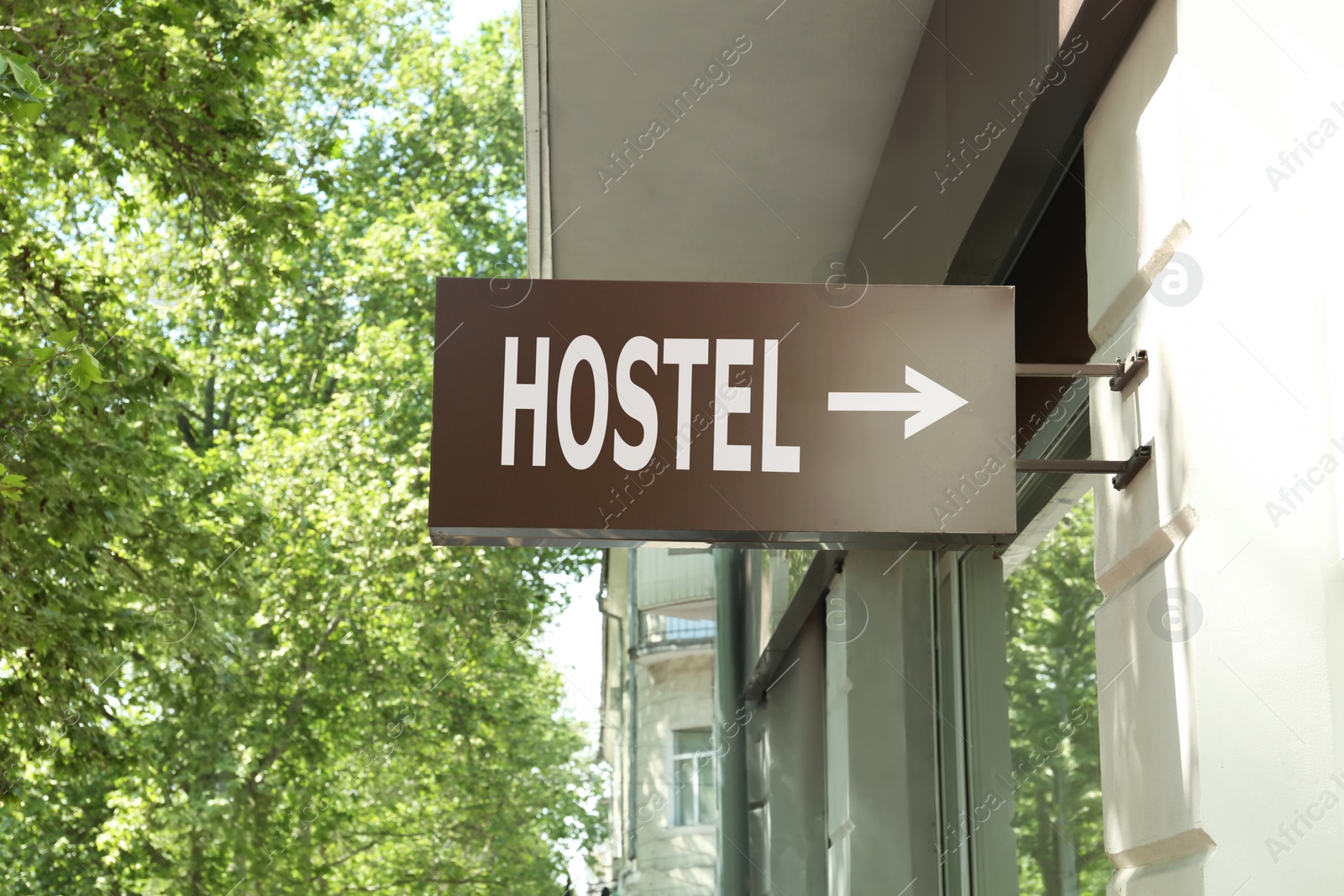 Image of HOSTEL lightbox signage with arrow on building wall outdoors