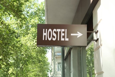 Image of HOSTEL lightbox signage with arrow on building wall outdoors