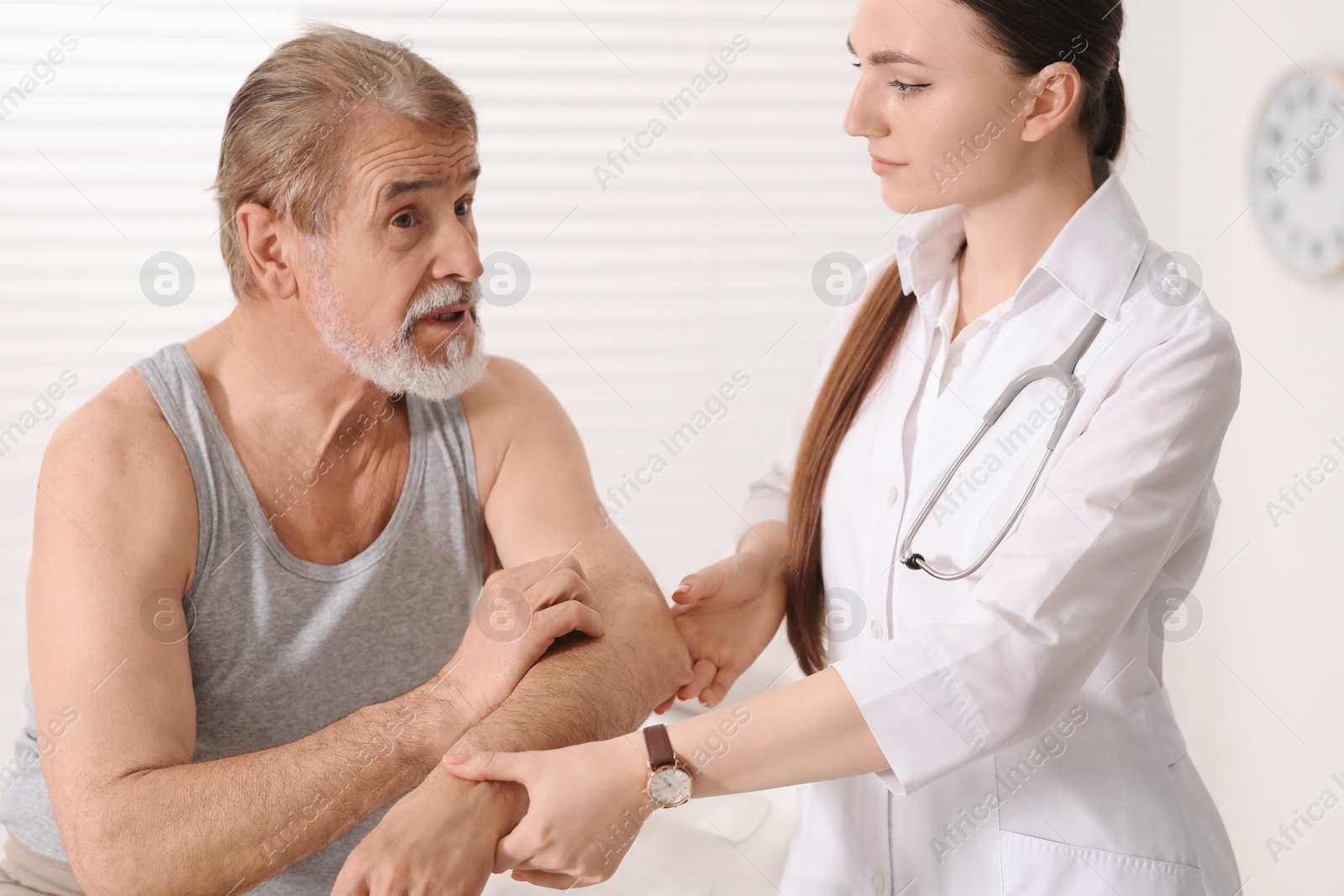 Photo of Orthopedist examining patient with injured arm in clinic