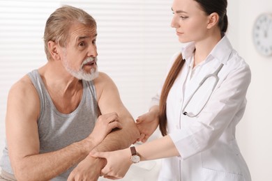 Orthopedist examining patient with injured arm in clinic