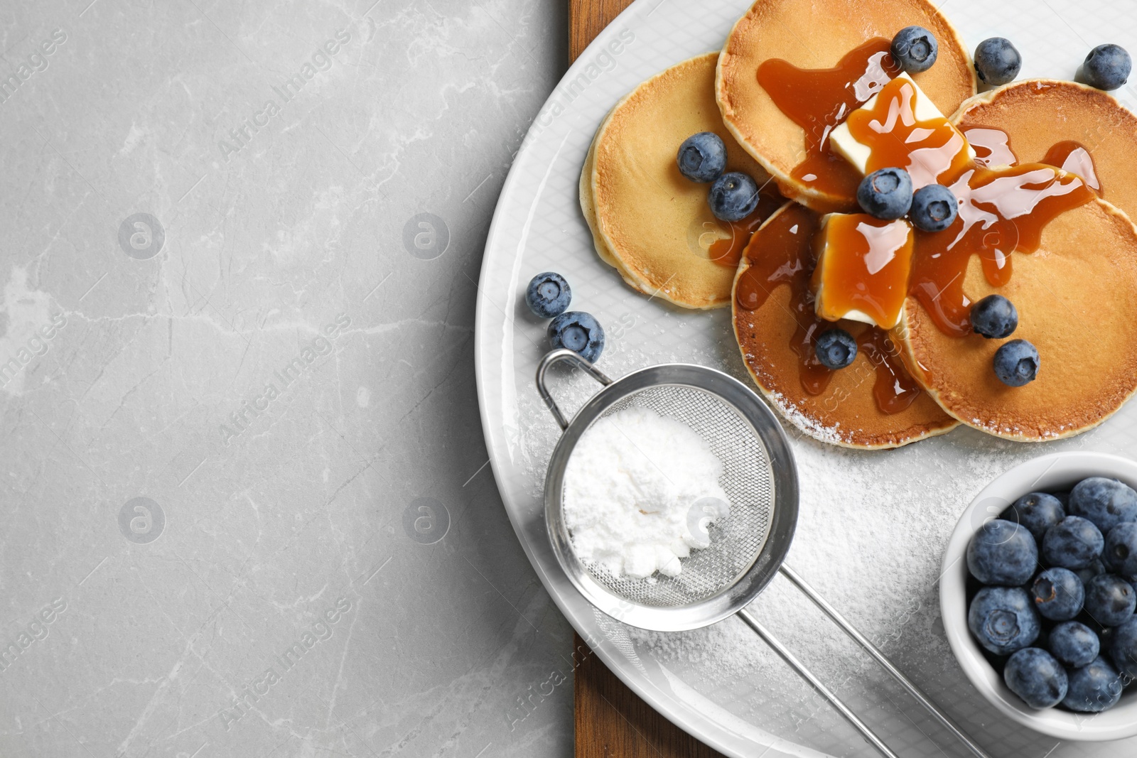 Photo of Tasty pancakes with blueberries served on grey marble table, flat lay. Space for text