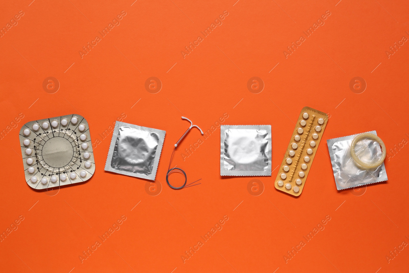 Photo of Contraceptive pills, condoms and intrauterine device on orange background, flat lay. Different birth control methods