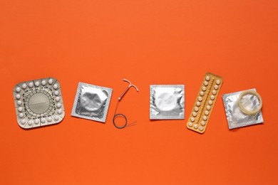 Contraceptive pills, condoms and intrauterine device on orange background, flat lay. Different birth control methods