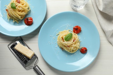 Photo of Tasty spaghetti with tomatoes and parmesan cheese served on white wooden table, flat lay. Exquisite presentation of pasta dish