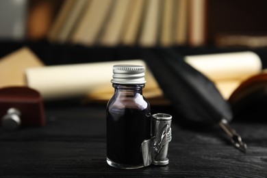 Photo of Feather pen and bottle of ink on black wooden table