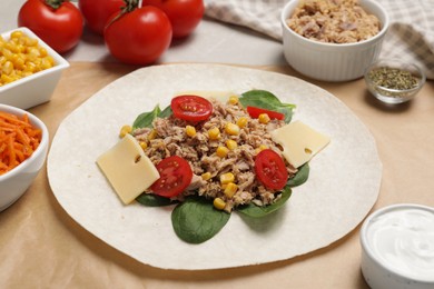 Photo of Delicious tortilla with tuna, vegetables and cheese on light table. Cooking shawarma