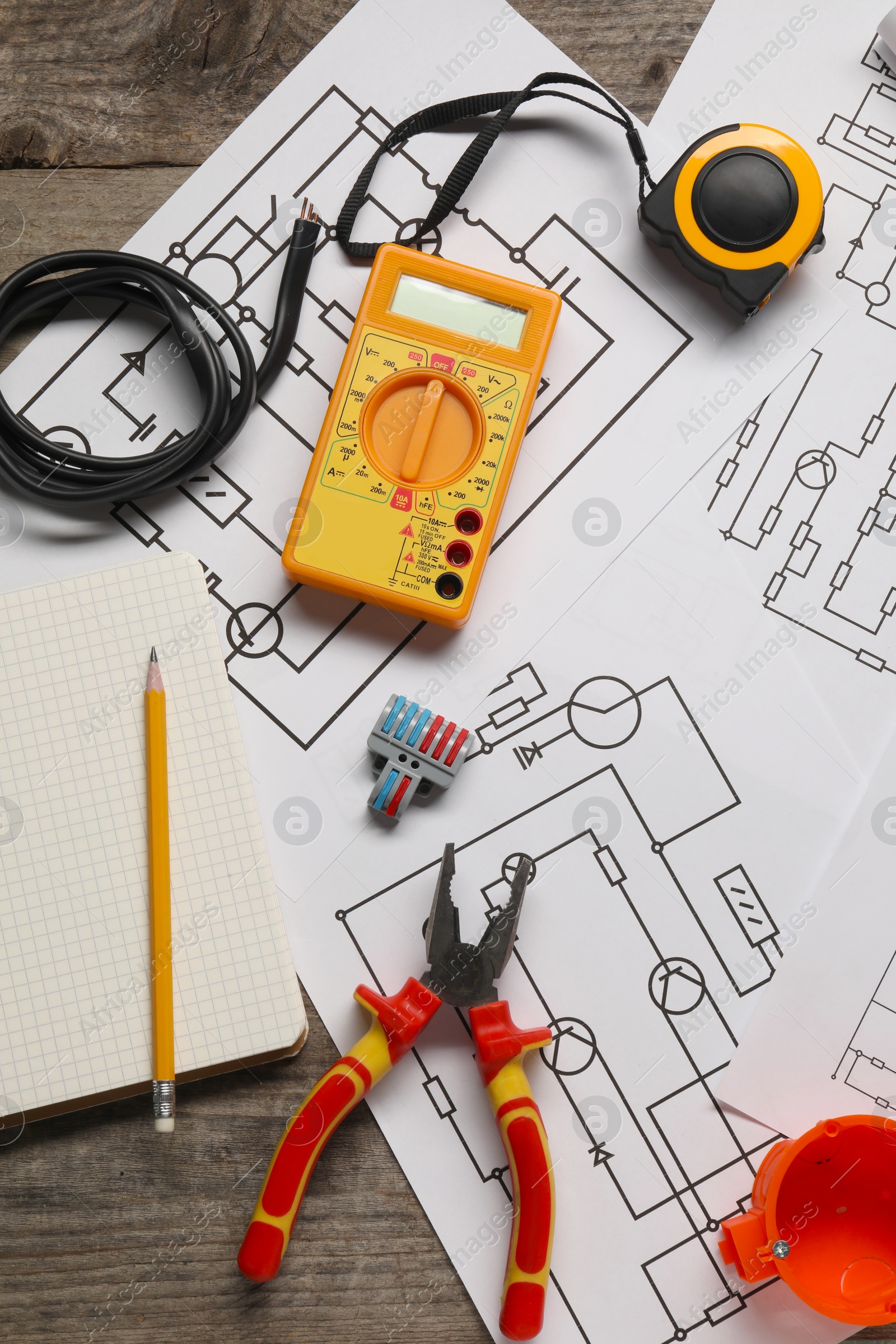 Photo of Flat lay composition with wiring diagrams and digital multimeter on wooden table