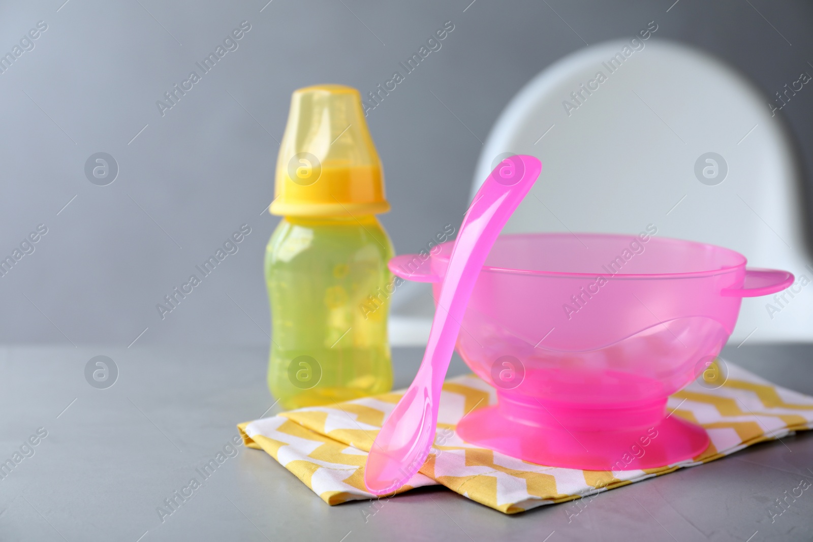 Photo of Set of plastic dishware on grey table. Serving baby food