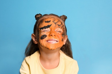 Cute little girl with face painting on blue background