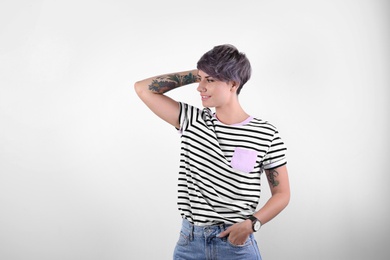 Trendy young woman with tattoos on white background