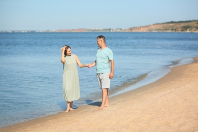 Photo of Happy mature couple holding hands at beach on sunny day