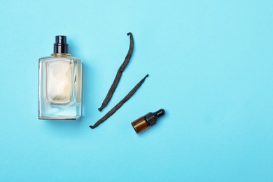 Bottles of perfume and vanilla pods on color background, top view