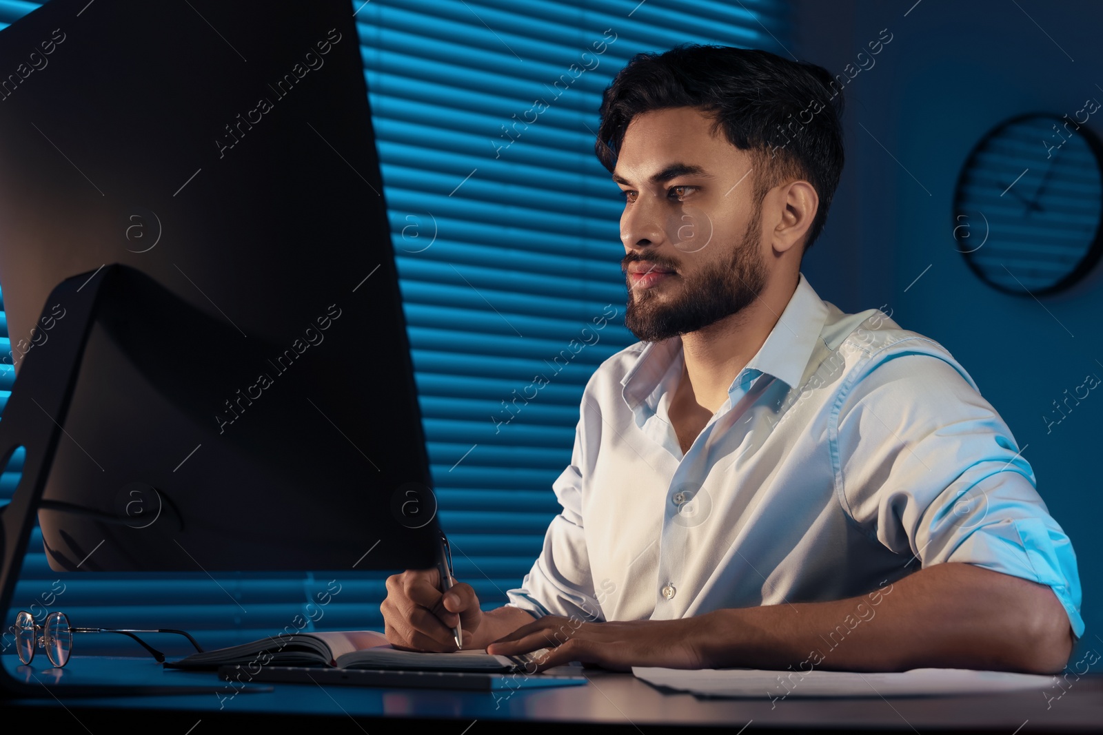 Photo of Tired young man working late in office