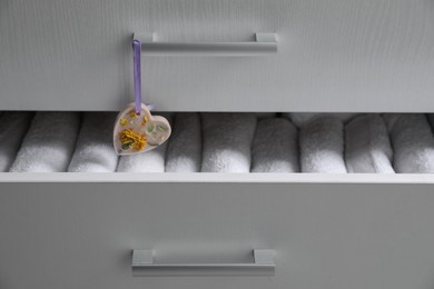 Photo of Chest of drawers with heart shaped scented wax sachet and towels, closeup