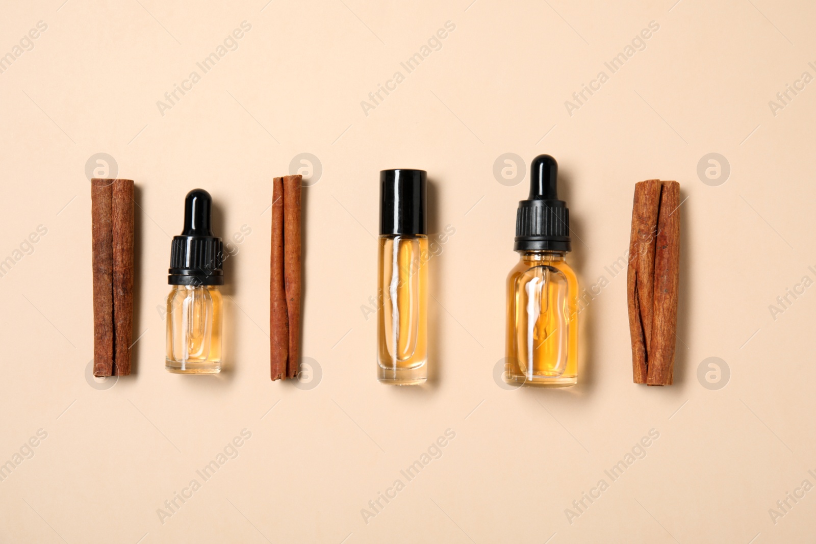 Photo of Flat lay composition with cinnamon essential oil on beige background