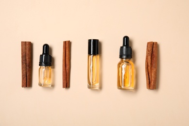 Photo of Flat lay composition with cinnamon essential oil on beige background